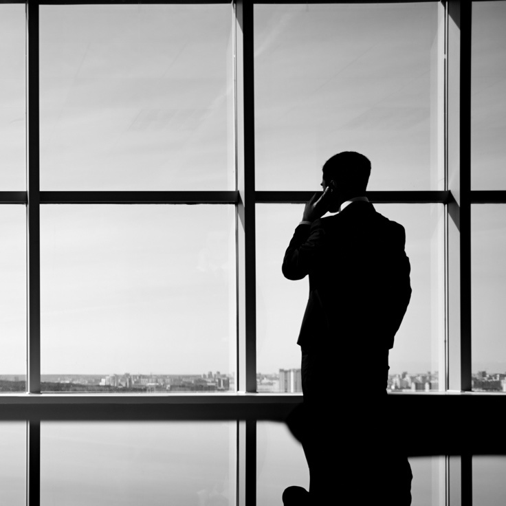 Man_in_phone_looking_out_window_grey_736.jpg